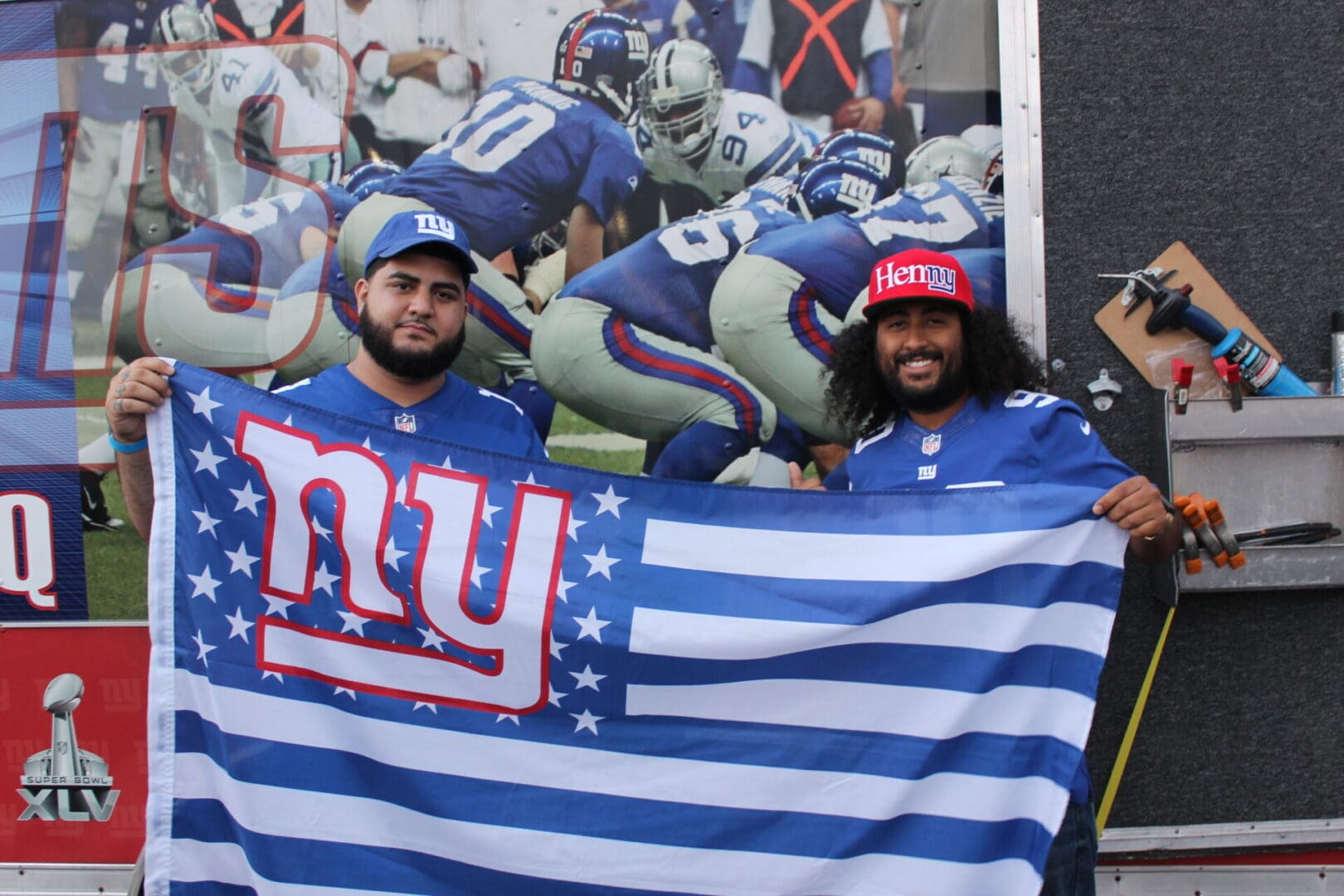Two men holding a flag in front of an image of the nfl.